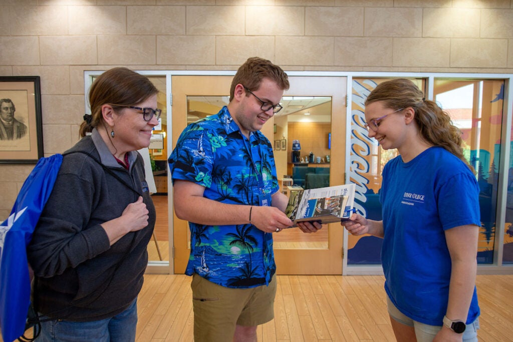 Three people look at a brochure outside of the Admissions Visit Center.