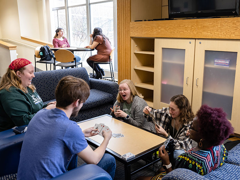 five Luther students playing cards while gathered around a table