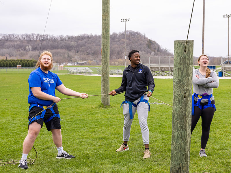 three Luther students at an outdoor ropes course