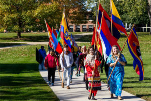 Luther students walking down a sidewalk while carrying various international flags