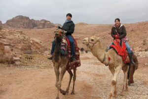 two Luther students riding camels in the desert