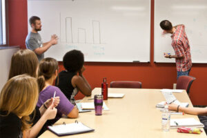 two Luther students using a whiteboard to present to a class