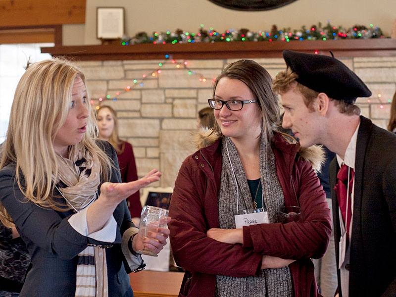 three people stand together, gesturing and smiling