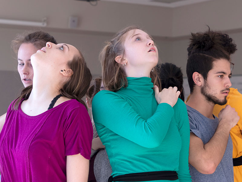 a group of dancers are in a circle back to back, looking up