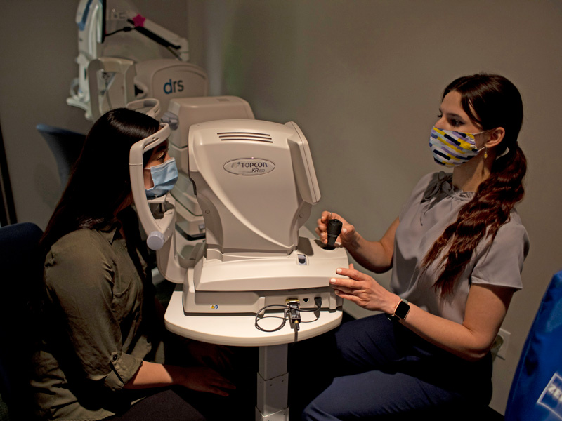 a student intern uses optometry equipment to examine a patient