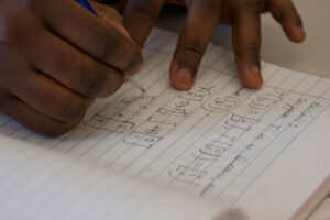 a Luther student working on a math equation in a notebook