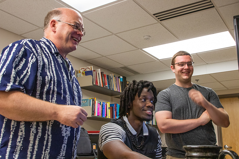 Professor Pedlar stands next to two students