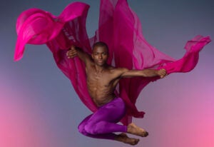 a dancer leaps into the air with billows of fabric