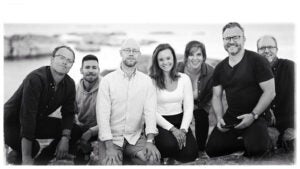 black and white photo of 7 people on their knees with a river in the background