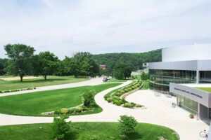 winding pathways and greenery in front and on the roof of a silver building with a large bank of windows