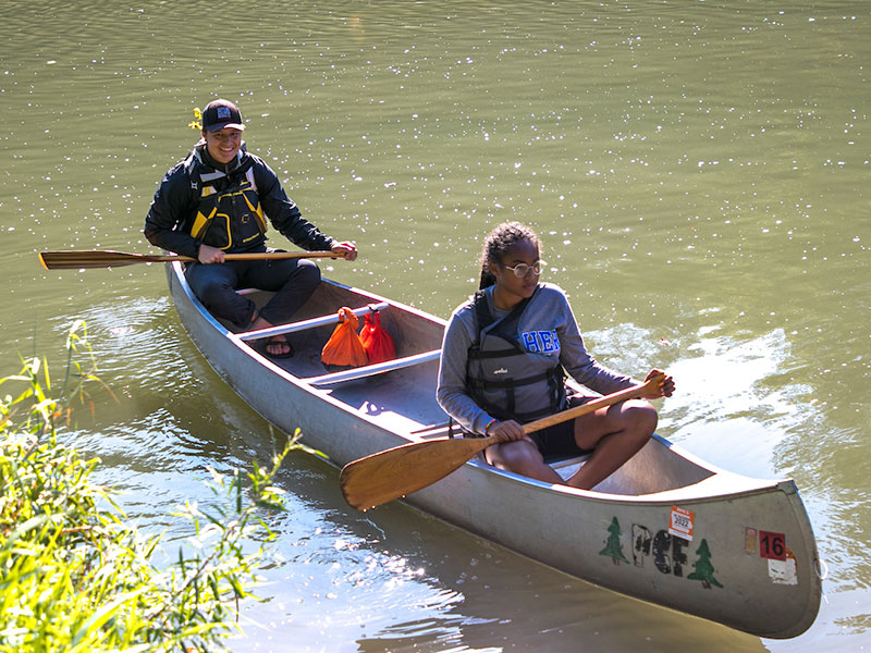 two Luther students in a canoe on a river