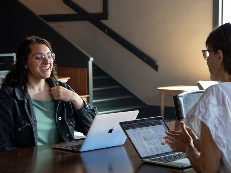 a Luther student and professor having a conversation at a table