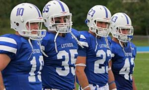Luther College football players preparing to begin a play on field