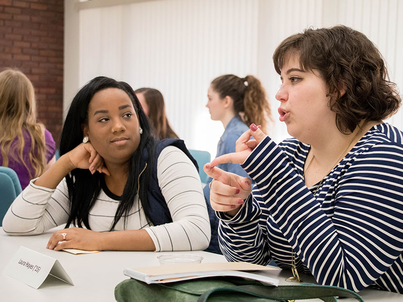 two women sit together, one is listening and the other talking