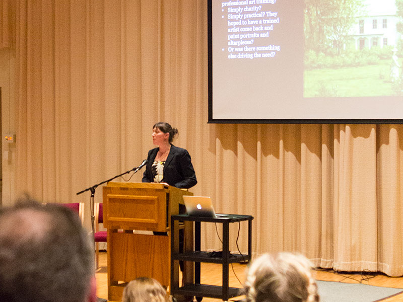 woman stands at a podium giving a lecture