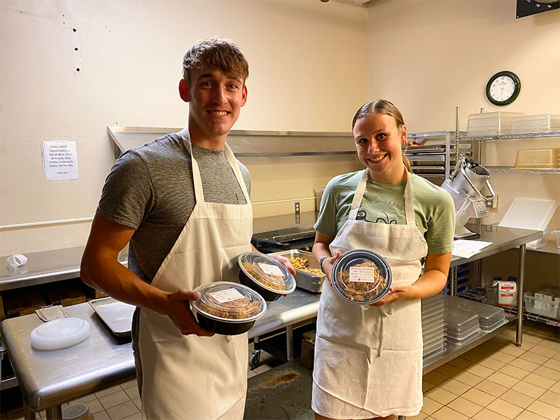 Photo of two Luther students displaying packaged food ready for donation