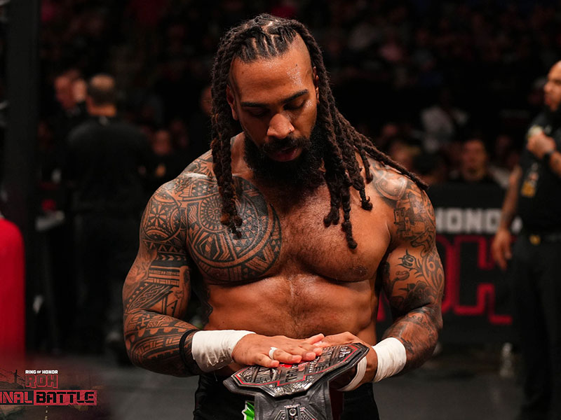 Photo of Jasper Kange looking down at a championship belt