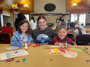 Photo of a Luther PALS volunteer with her arms around a Decorah-area child on either side of her