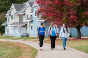Three students walking through Baker Village in the fall.