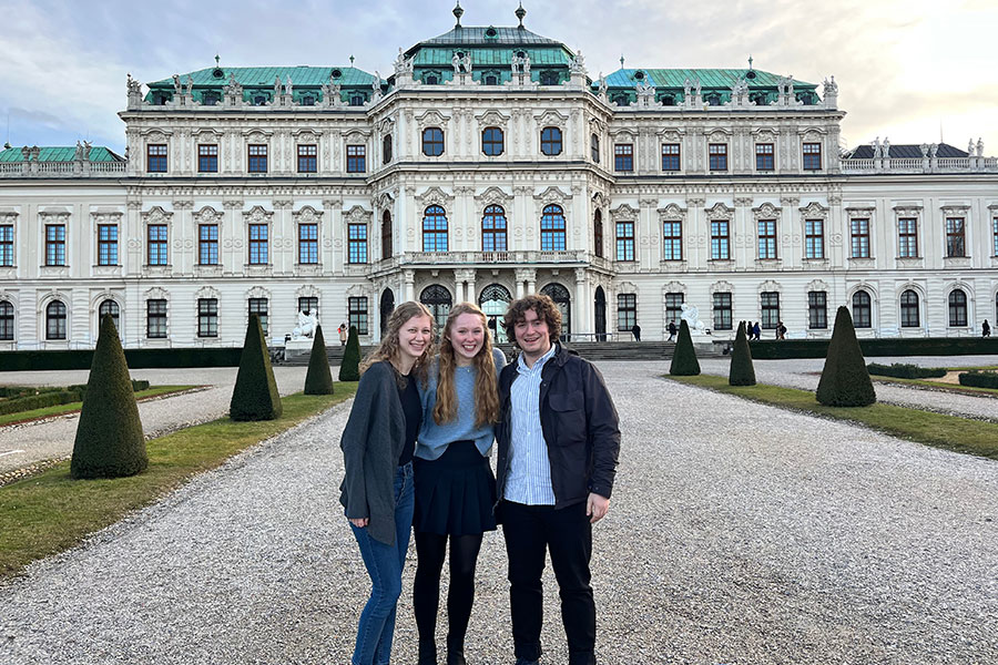 Three students standing in front of a castle