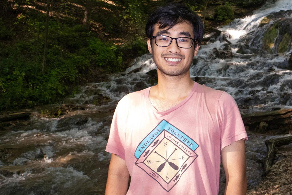 Minh Nguyen stands outside with a waterfall in the background.