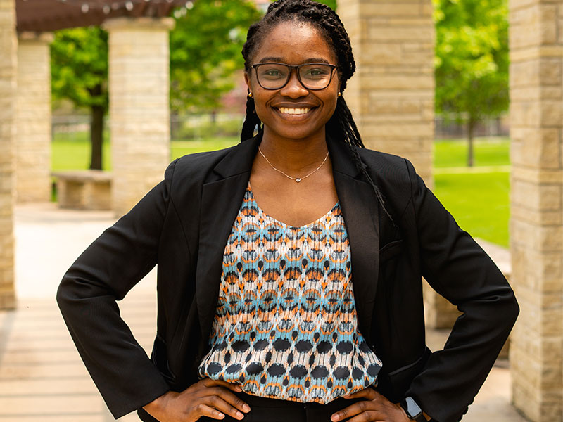 A smiling woman standing with her hands on her hips