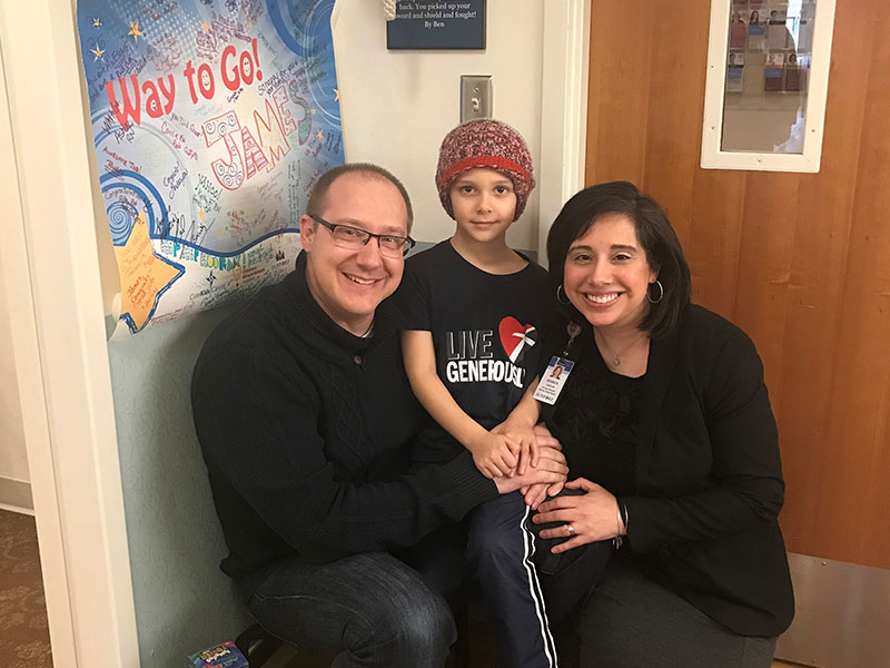 A man and woman crouch with a boy standing between them inside a hospital