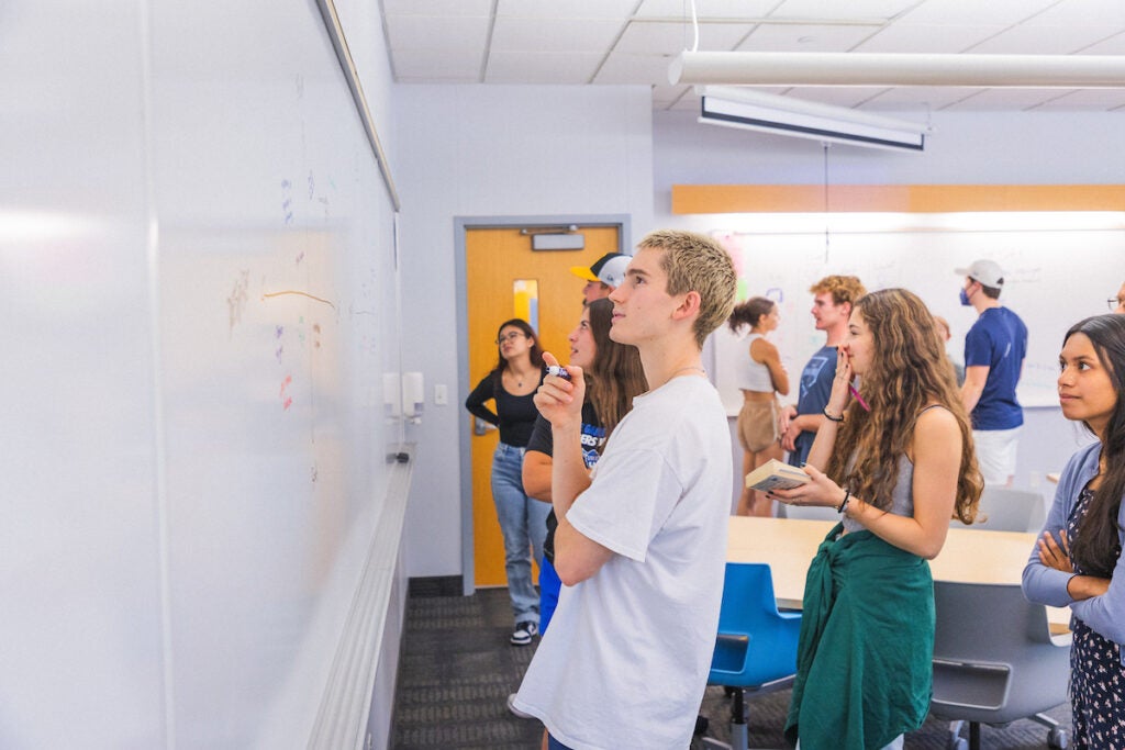 several students look at a whiteboard together