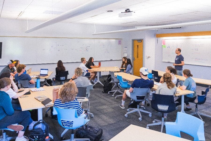 In a classroom, students sit around tables.