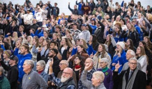 Luther College fans stand and cheer during a special announcement at Regents Center.