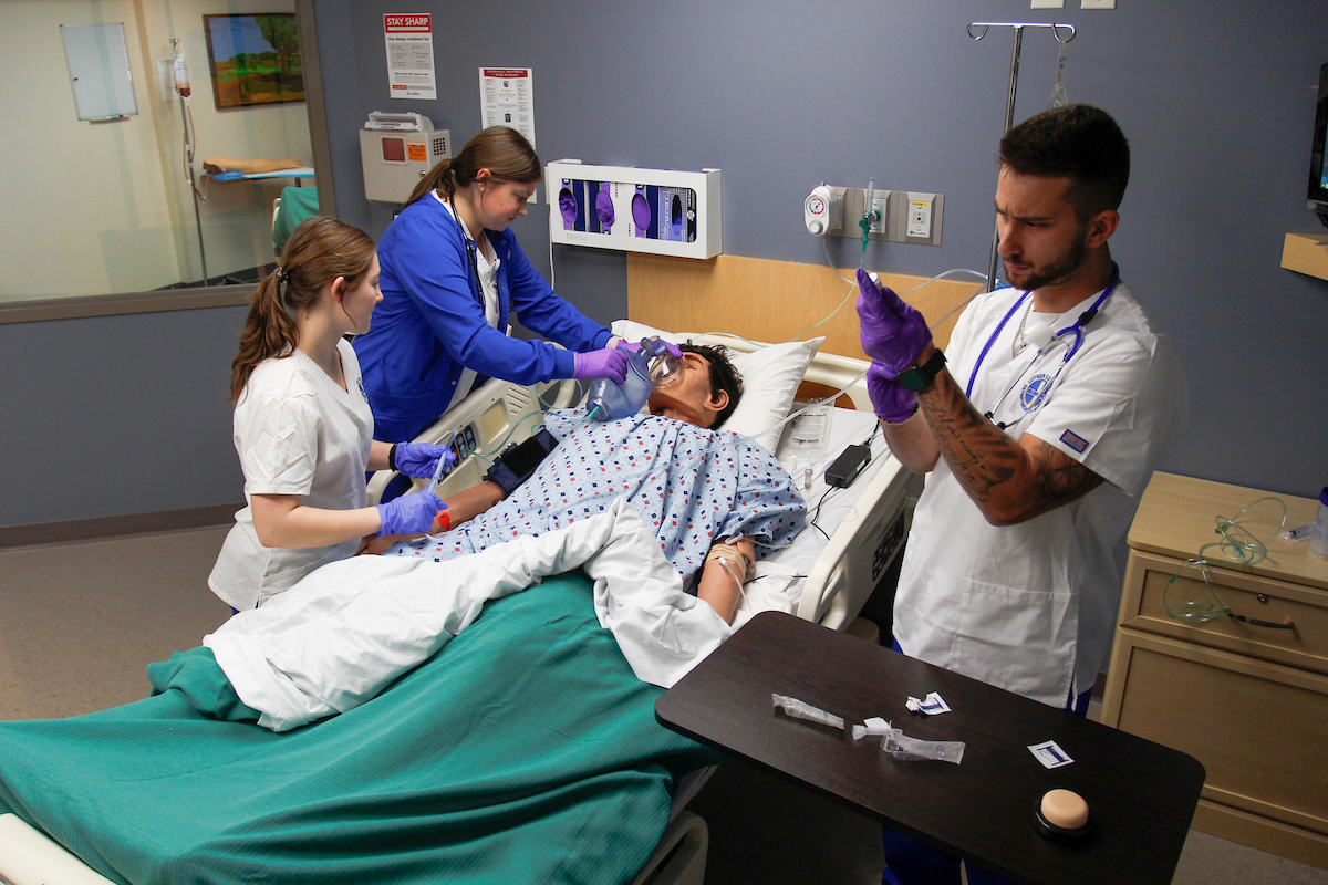Luther College nursing students working on a medical simulation doll.