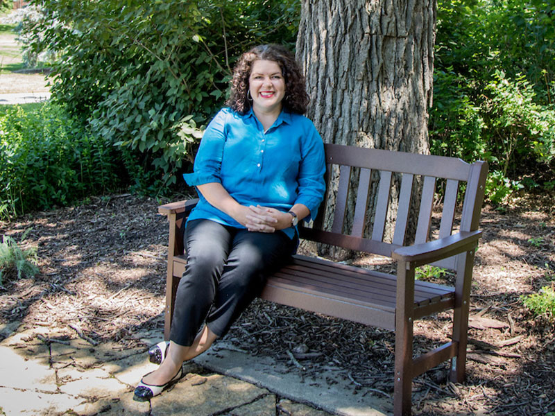 A woman sitting on a bench under a tree