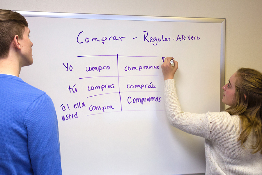 Two Luther College students writing on a whiteboard.