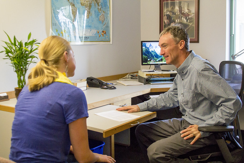 Steve Holland speaking with a Luther College student in his office.