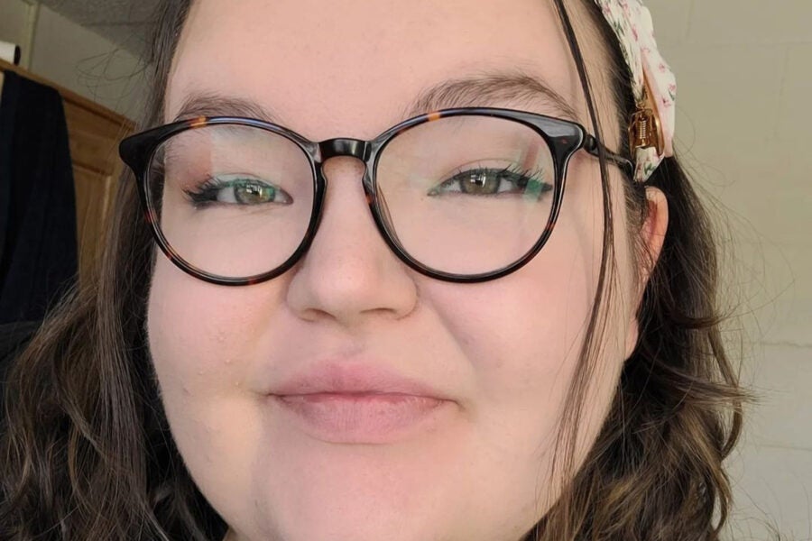 Grace head shot; she wears glasses and a head band in her hair.