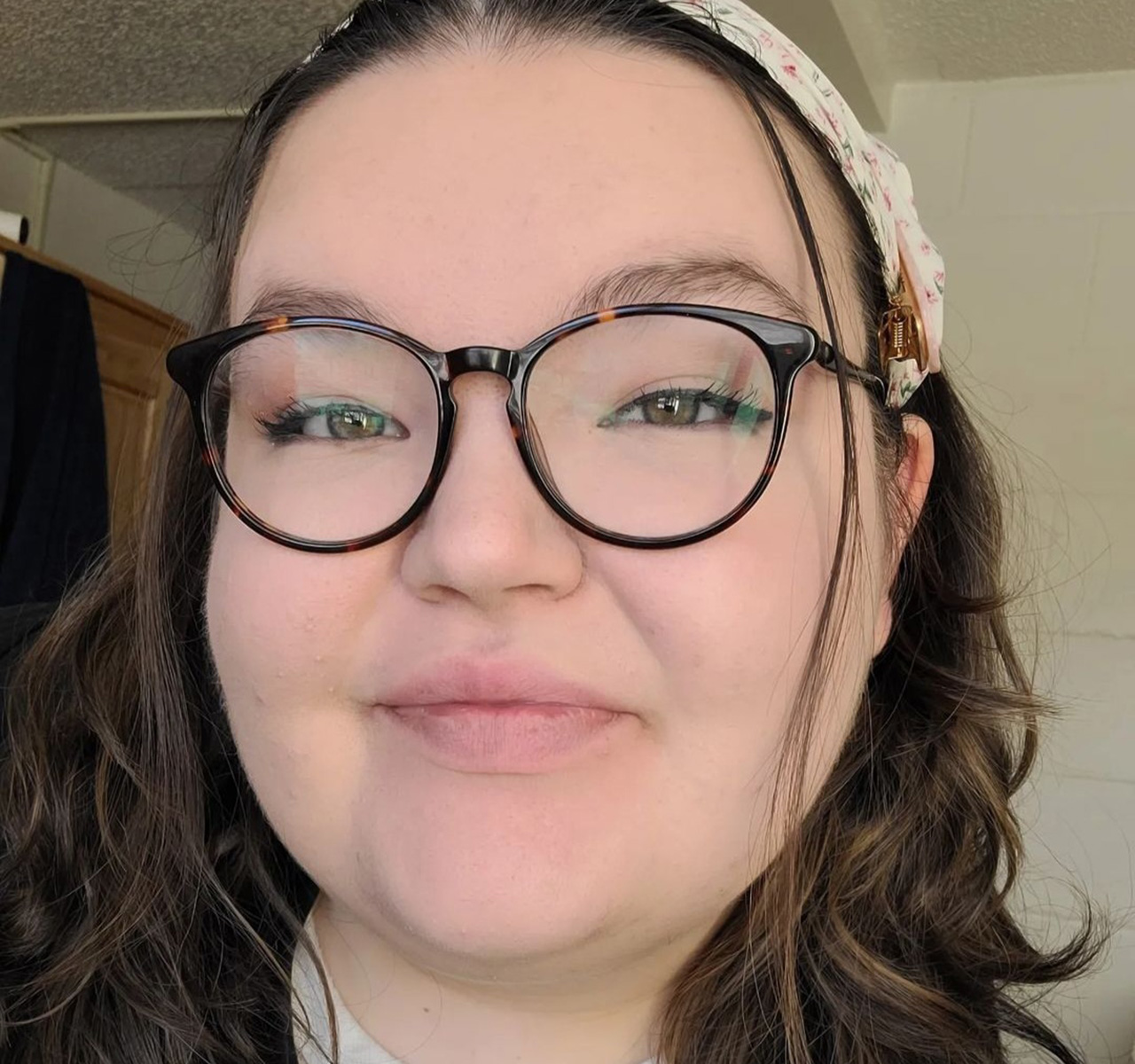 Grace head shot; she wears glasses and a head band in her hair.