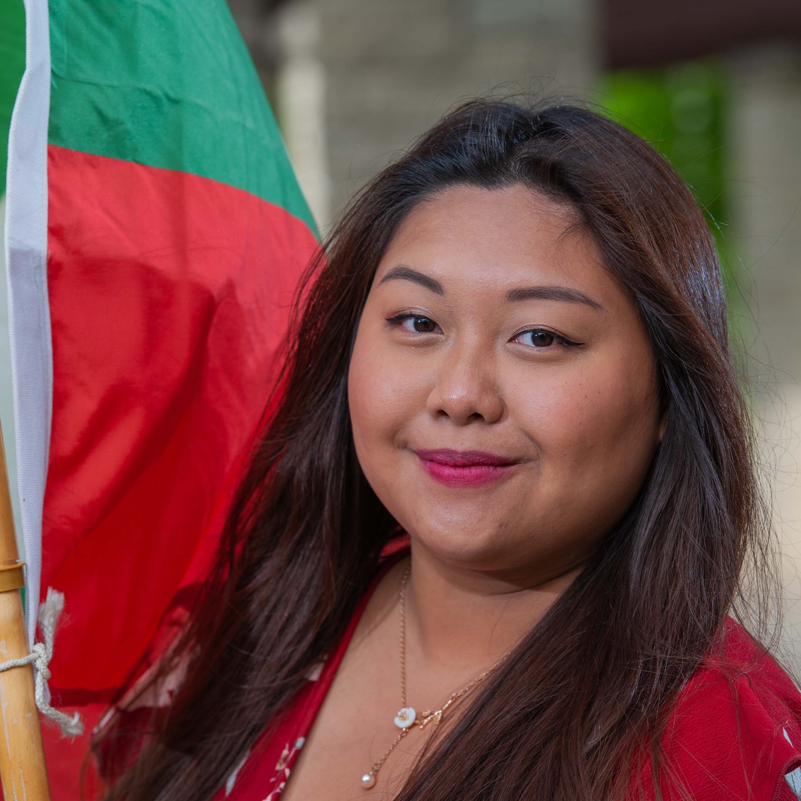 Nora stands in front of the Myanmar flag