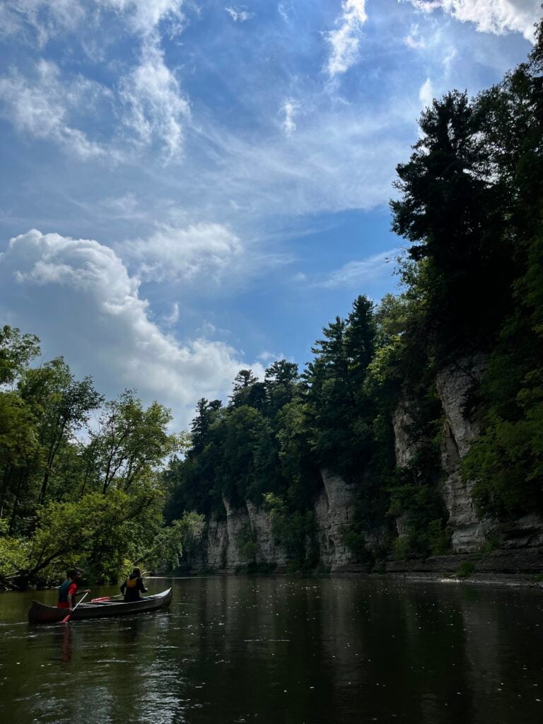 Bluffs along the Upper Iowa River with a kayaker floating by. 