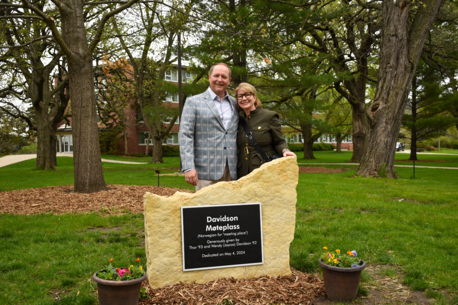 A couple stands in front of a stone.