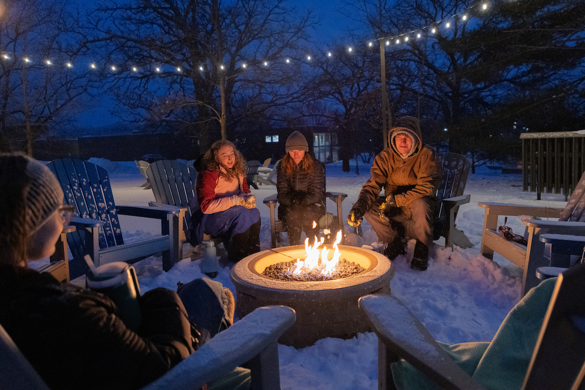 Three Students enjoying a bonfire night in the snow.