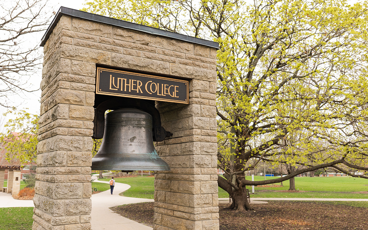 Bell between two stone columns with sign above that says "Luther College."