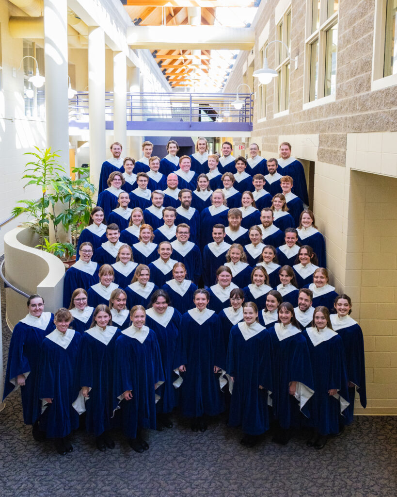 A group of college students in blue choir robes posing for a photo. 