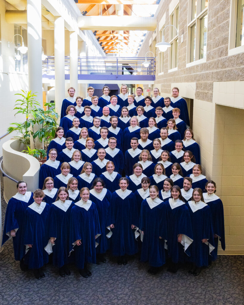 A group of college students in blue choir robes posing for a photo.
