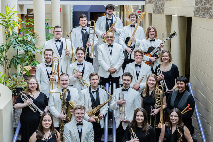 Students stand on stairs posing with different instruments.