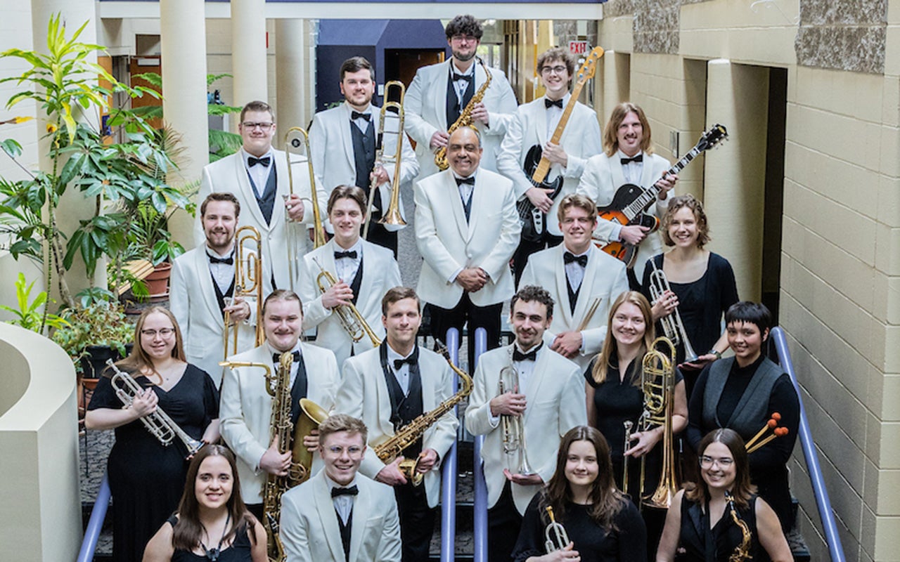 Students stand on stairs posing with different instruments.