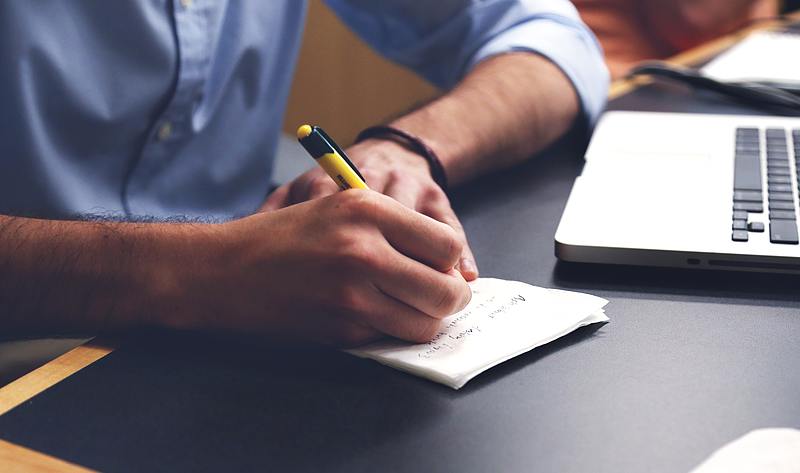 person using yellow pen to take notes