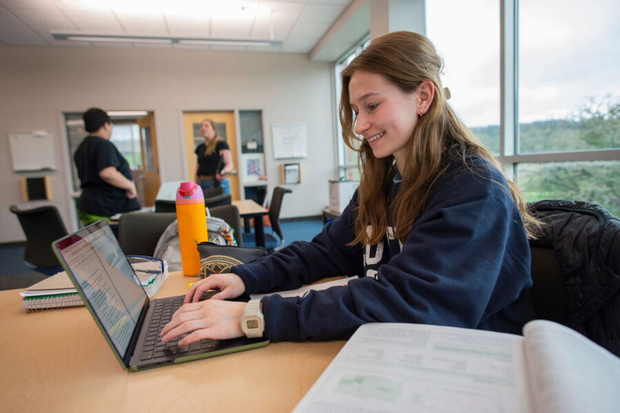 student studies in Samhoff Lounge with a smile