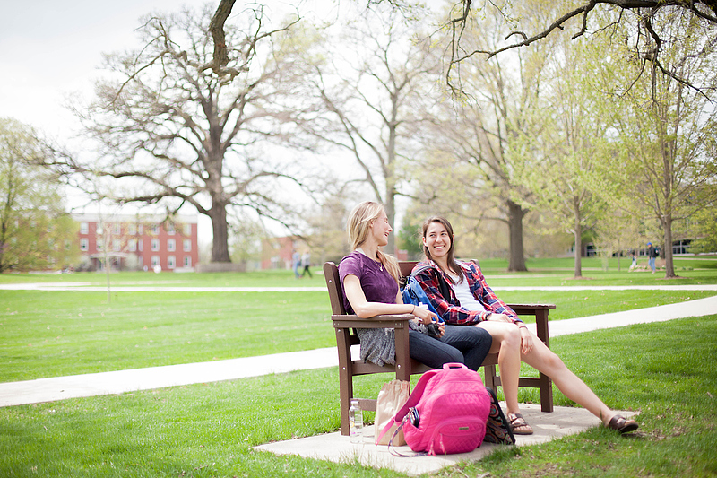 students sit on bench outside
