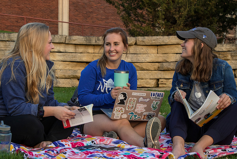 A student leans over a table. Tablecloth on the table says Phi Beta Kappa and shows the golden key of Phi Beta Kappa.