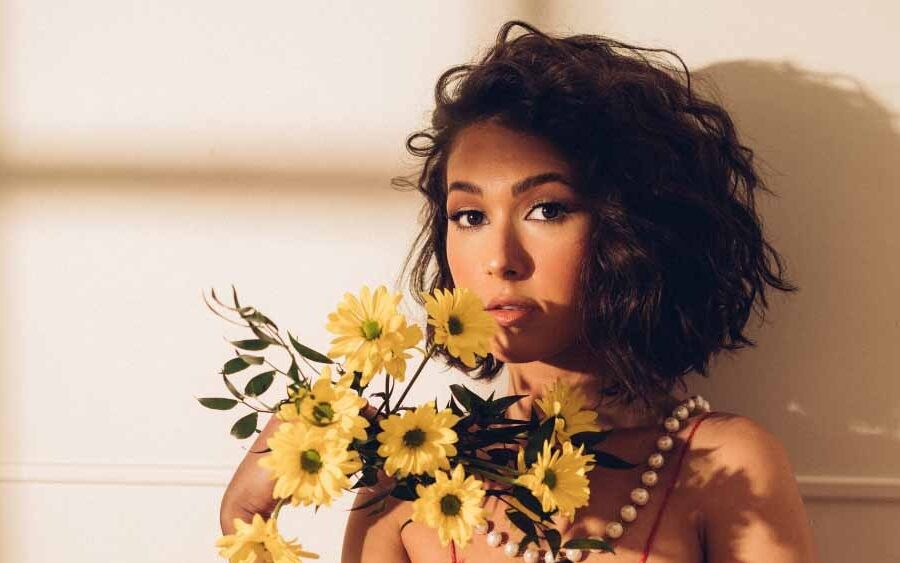 Nella in a red sundress holding yellow flowers